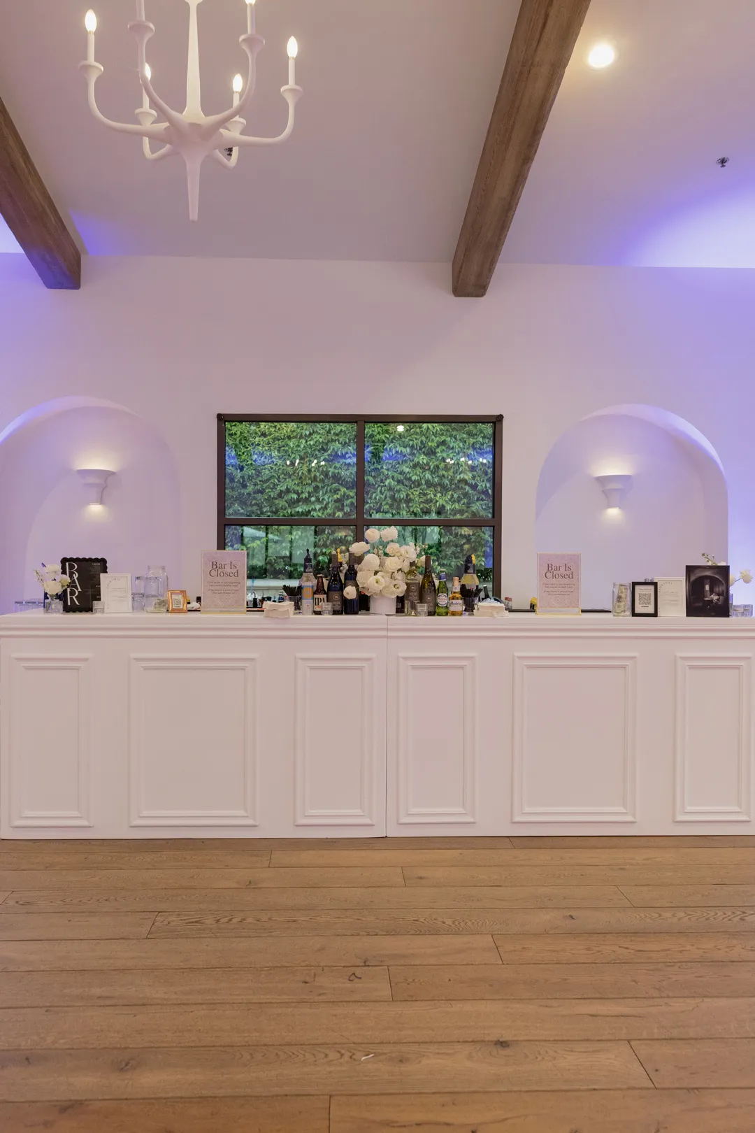 White bar beneath chandeliers and purple accent lighting.