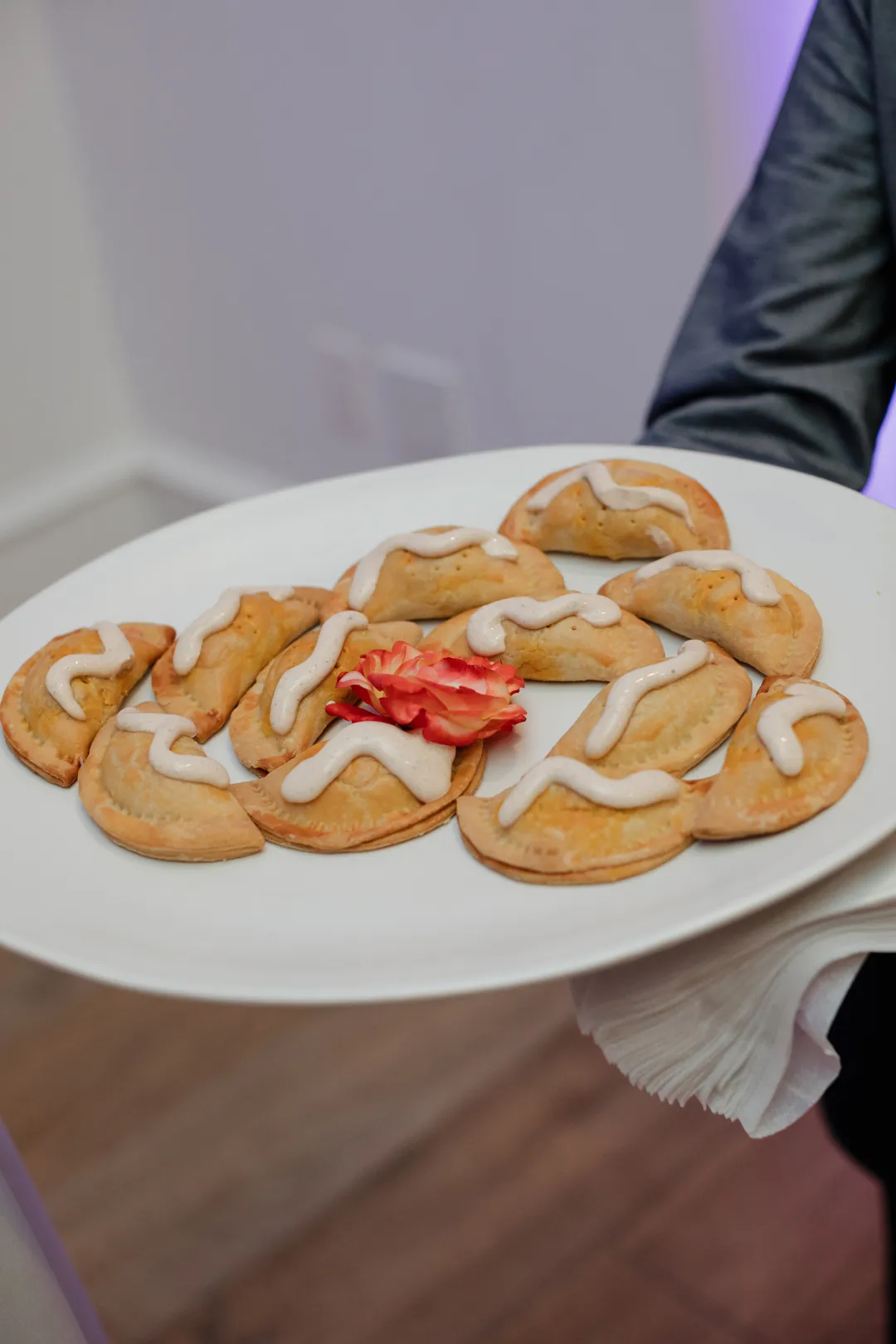 Tray-passed golden pastry appetizers topped with sauce.