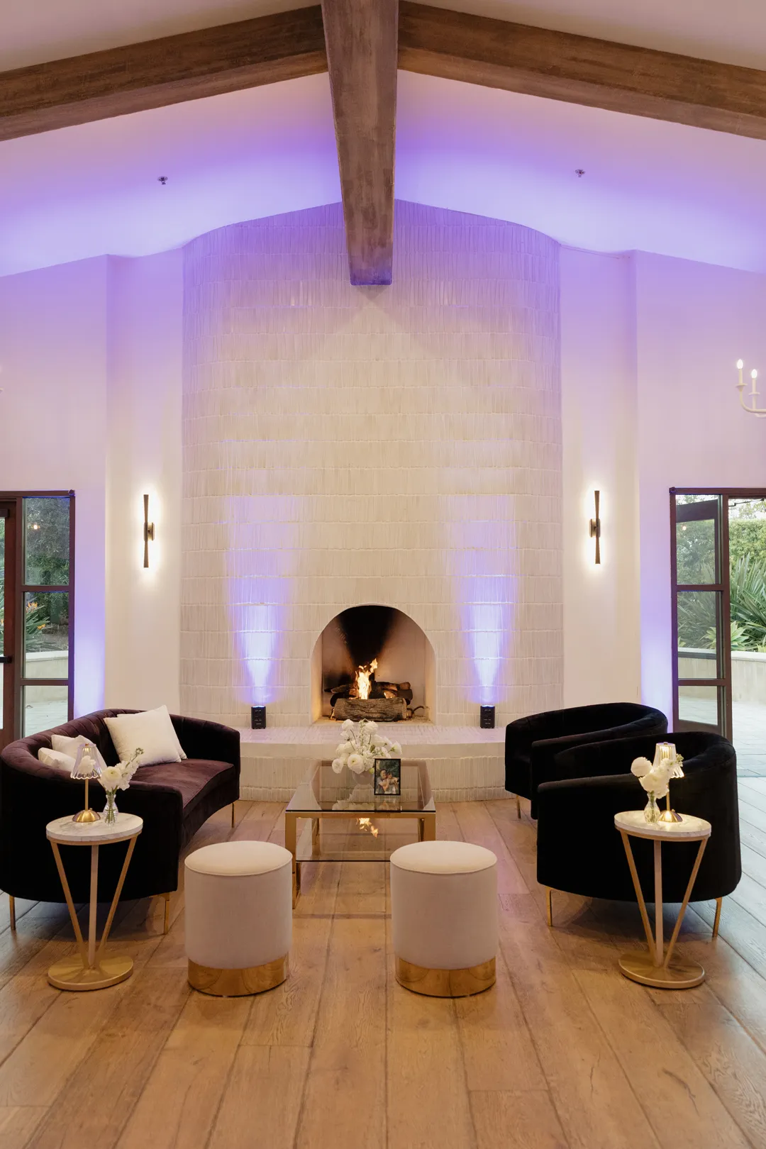 Black lounge chairs and small tables arranged in front of a fireplace.