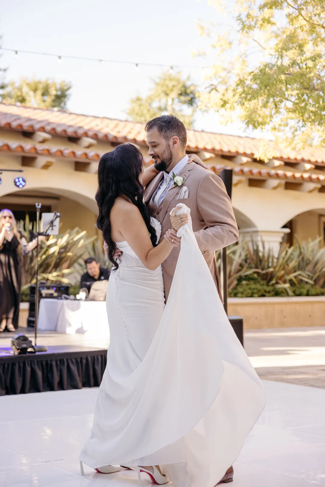 Wedding couple dancing together on the white courtyard dance floor.