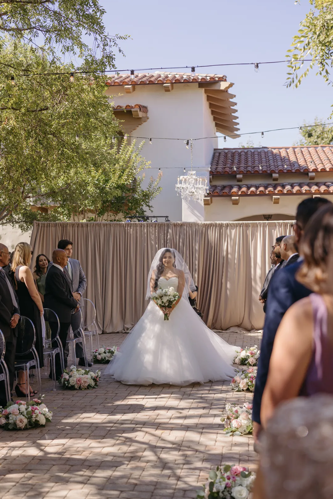 Bride entering the courtyard ceremony with her bouquet.