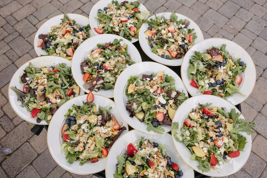 Plated green salads topped with berries and sliced almonds.