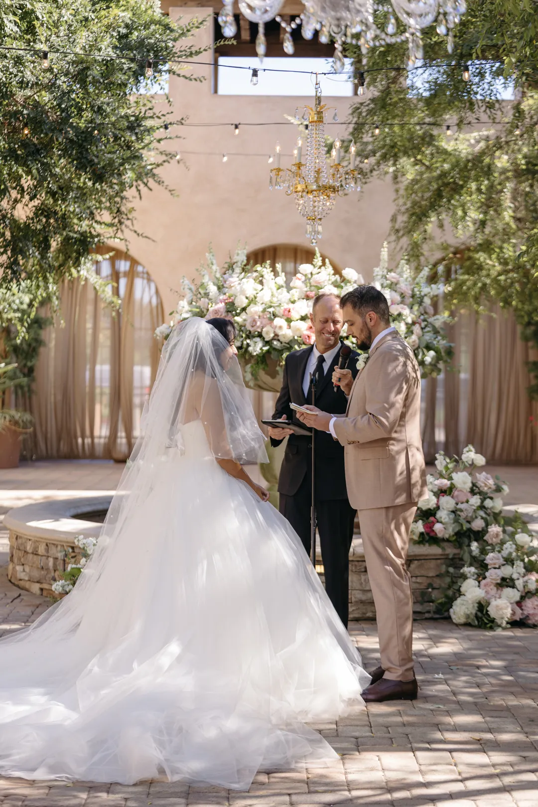 Wedding couple exchanging vows beside the flower-decorated fountain.