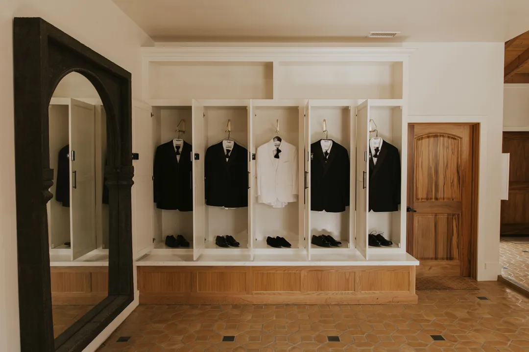 Black and white wedding jackets displayed in individual dressing-room cubbies.