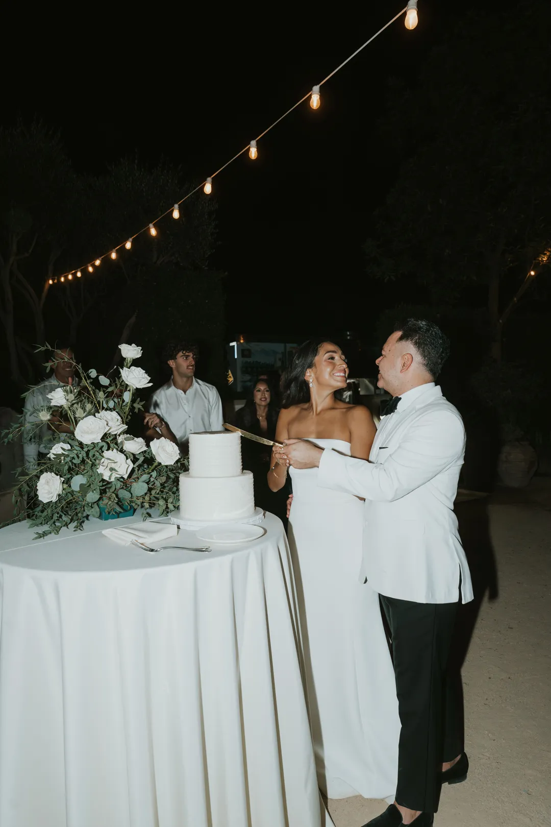 Wedding couple feeding each other cake beside their cake table.