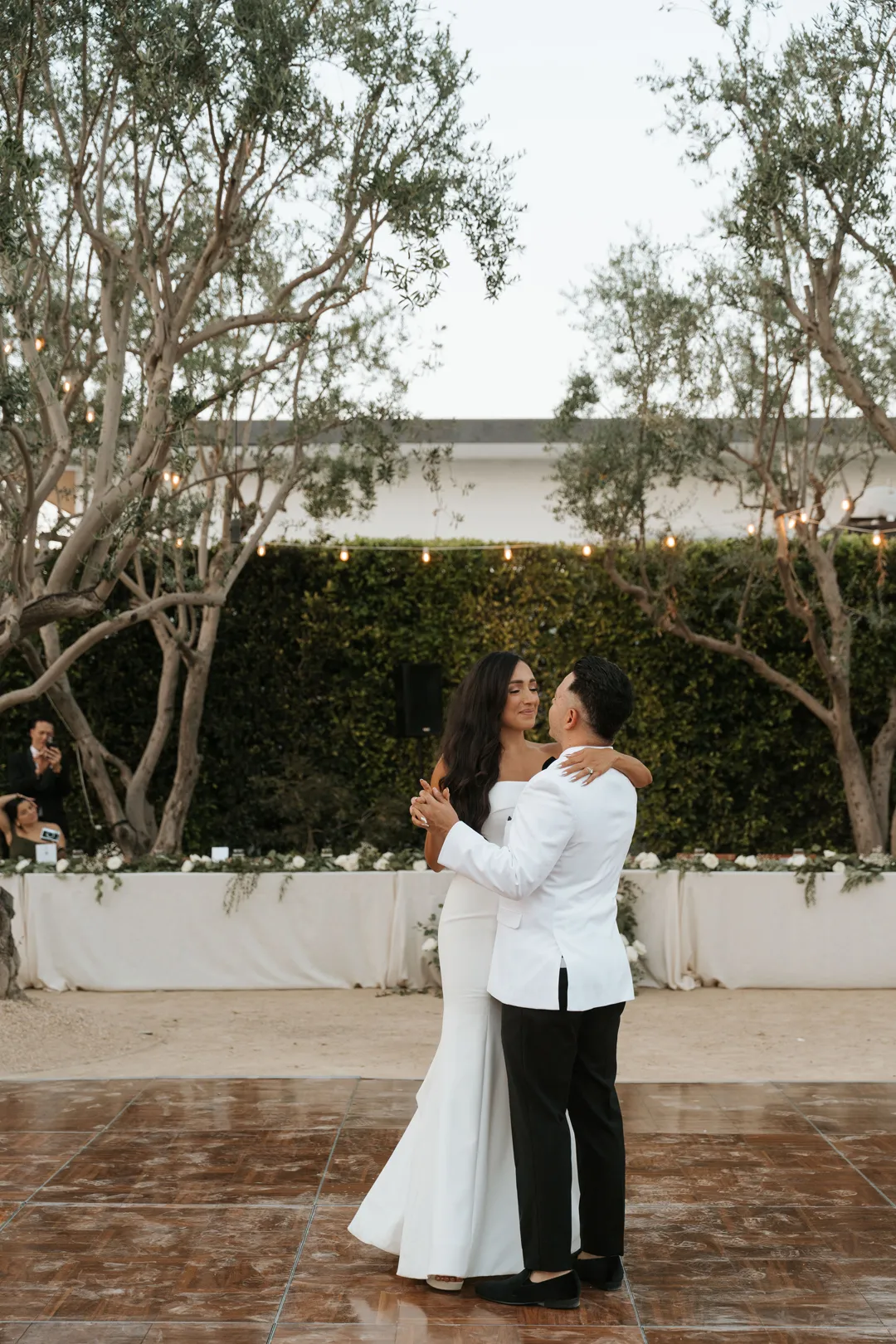Wedding couple sharing their first dance on an outdoor wooden dance floor.
