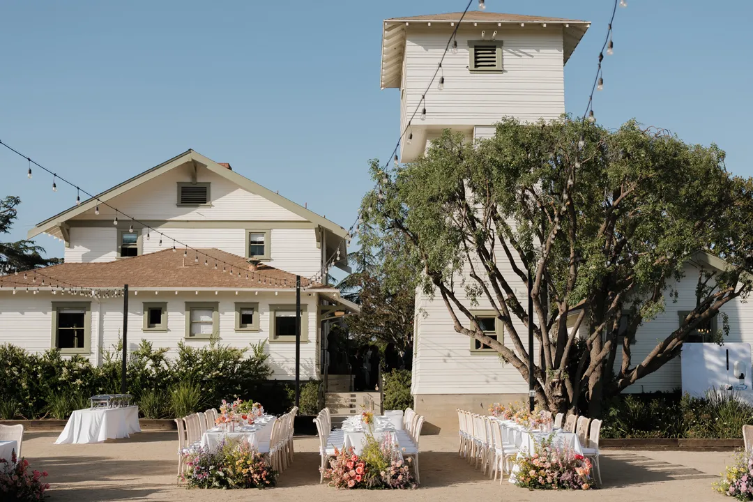 Reception seating and flowers outside a white historic-style building.