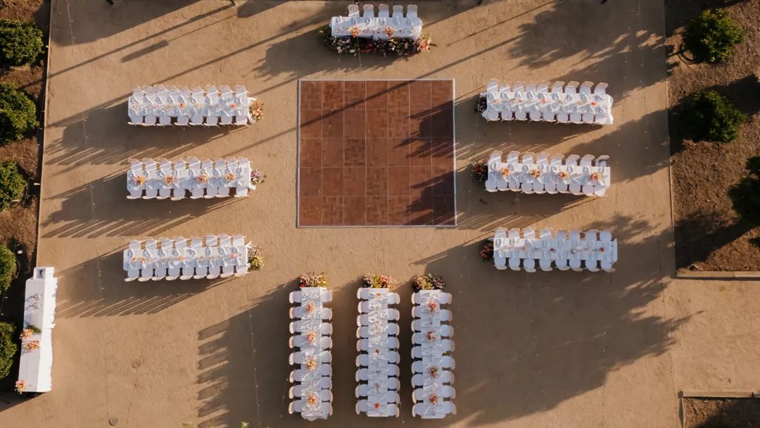Overhead view of outdoor reception tables arranged around a wooden dance floor.