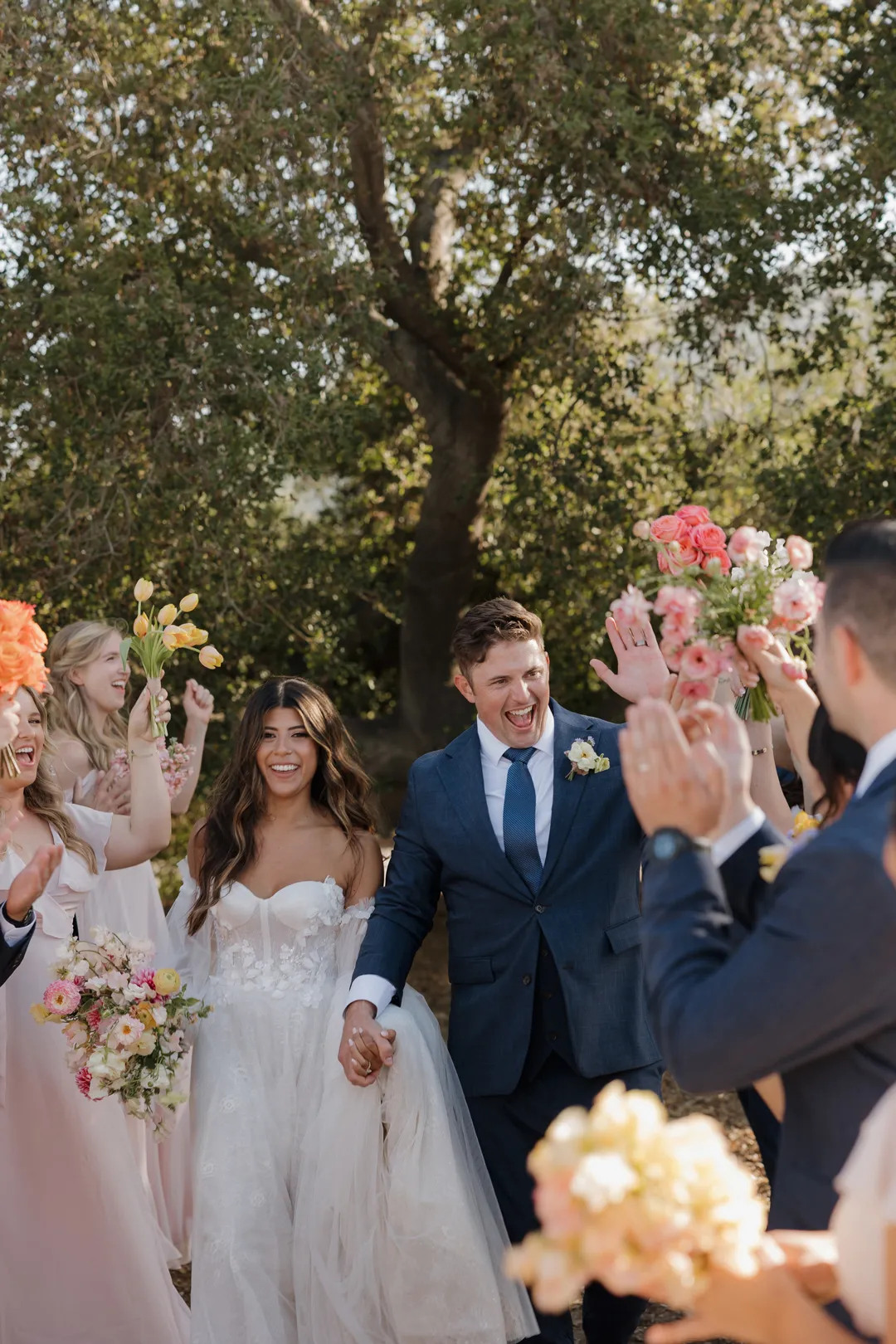 Newlyweds walking between applauding guests after their ceremony.