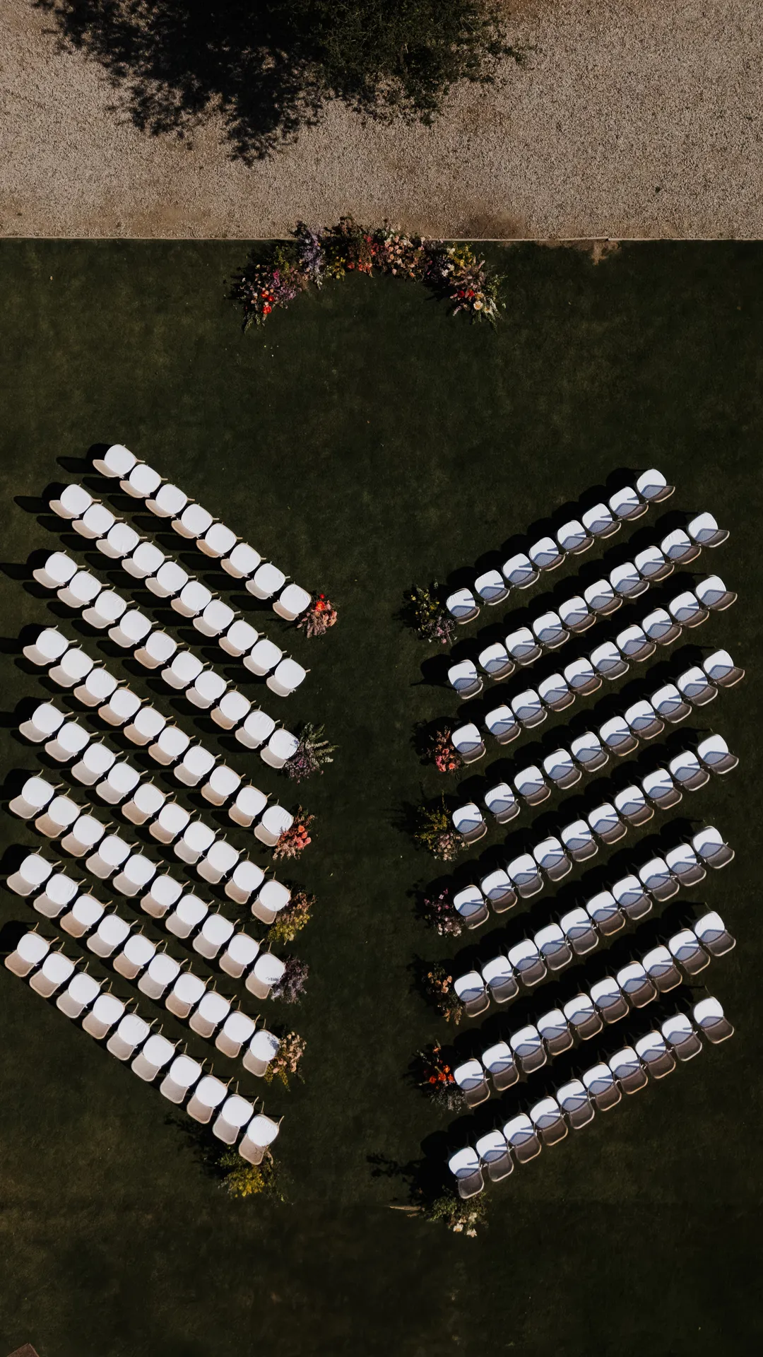 Overhead view of ceremony chairs arranged on either side of a lawn aisle.