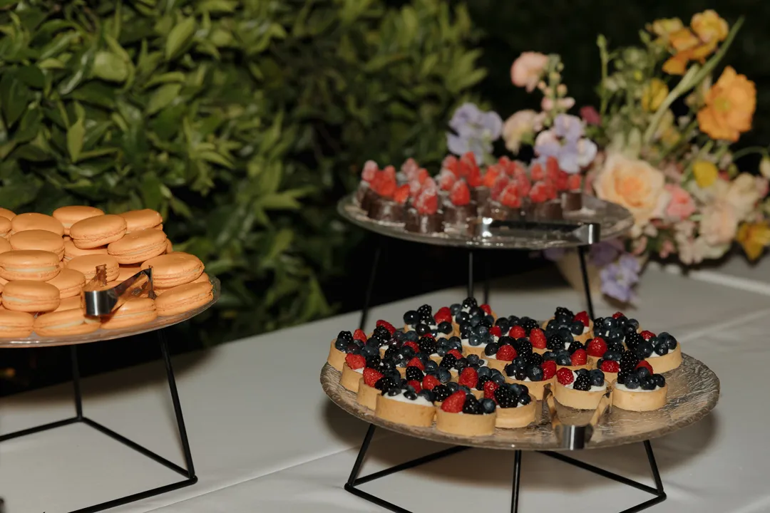 Fruit tarts and macarons displayed on raised dessert platters.