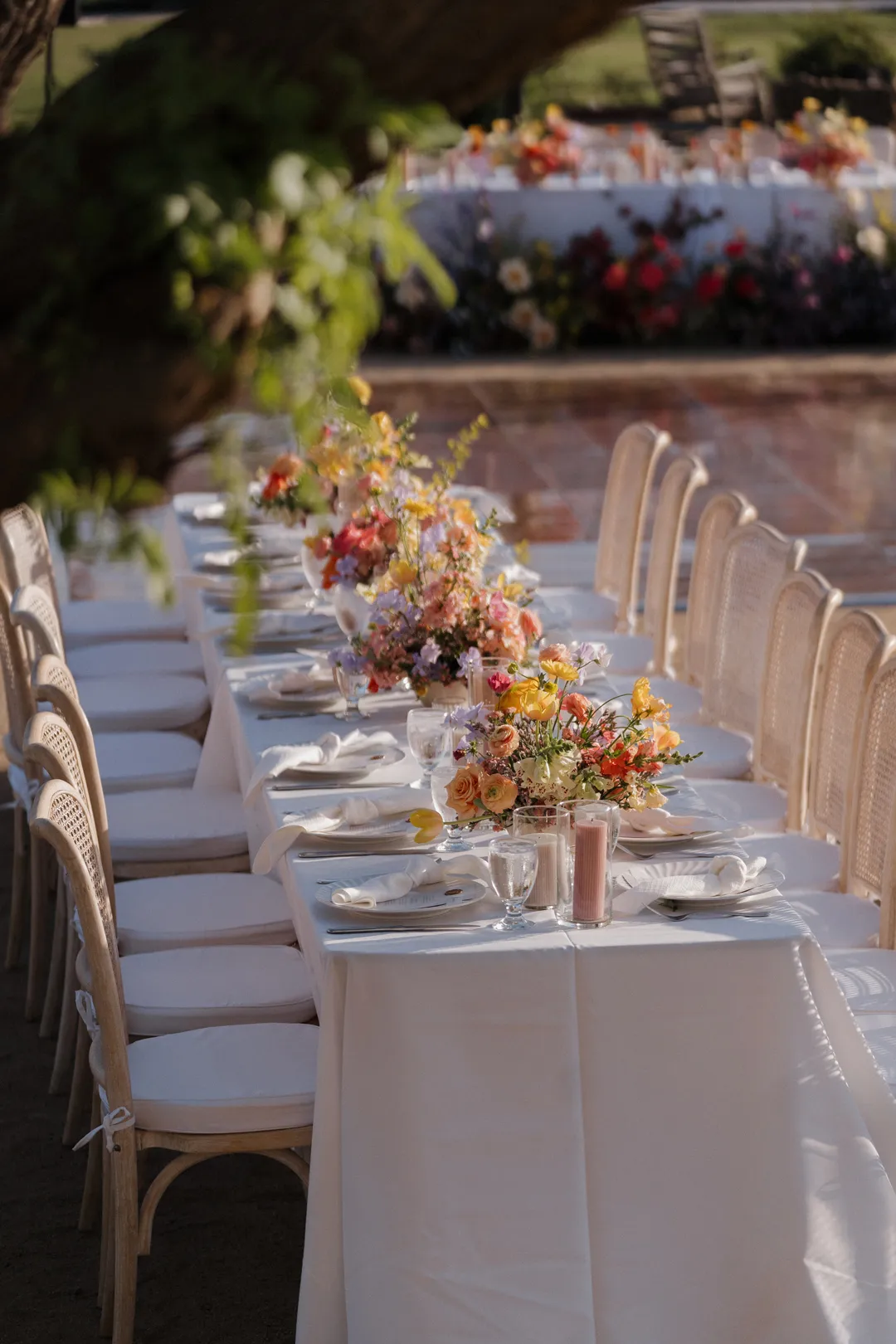 White-linen reception table set with colorful flowers and candles.