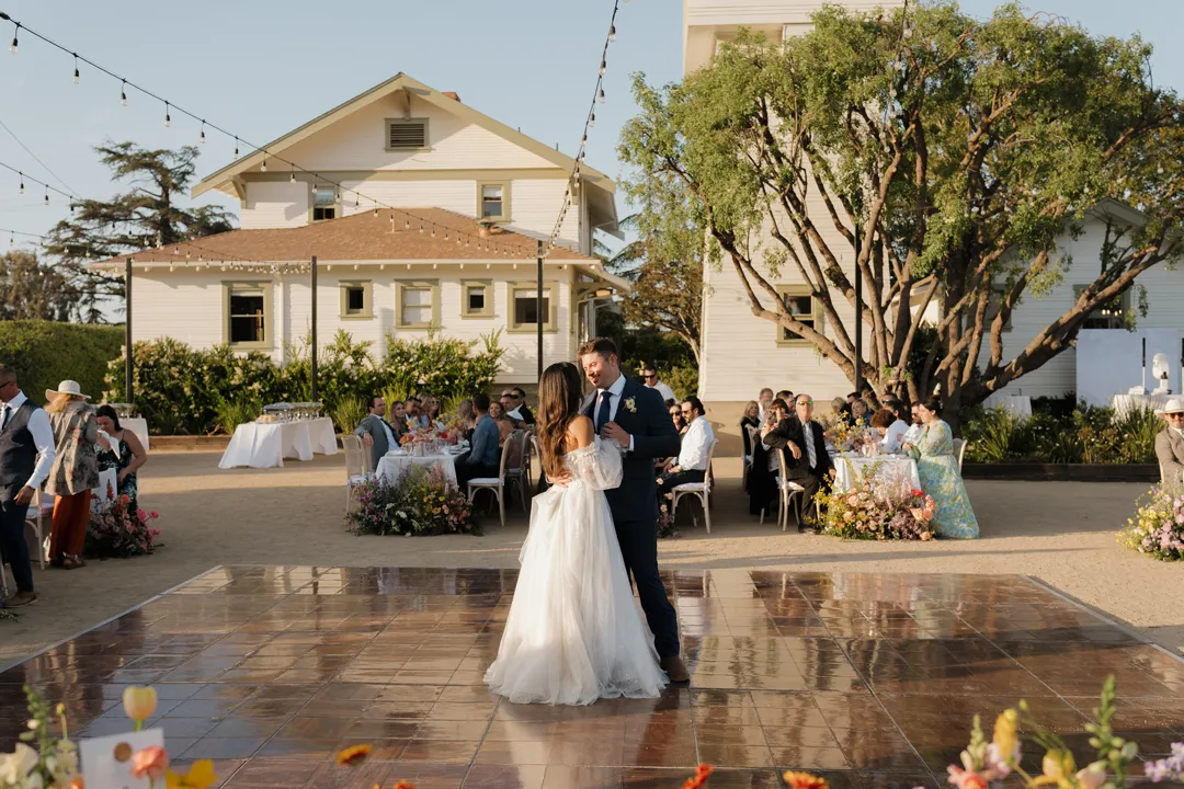 Wedding couple sharing their first dance outside a white building.