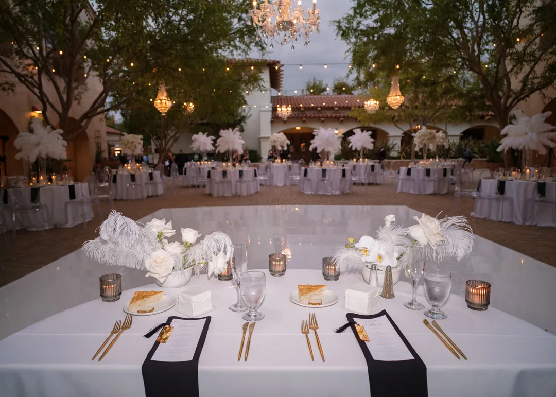 Sweetheart table with white flowers and feathers overlooking the courtyard reception.
