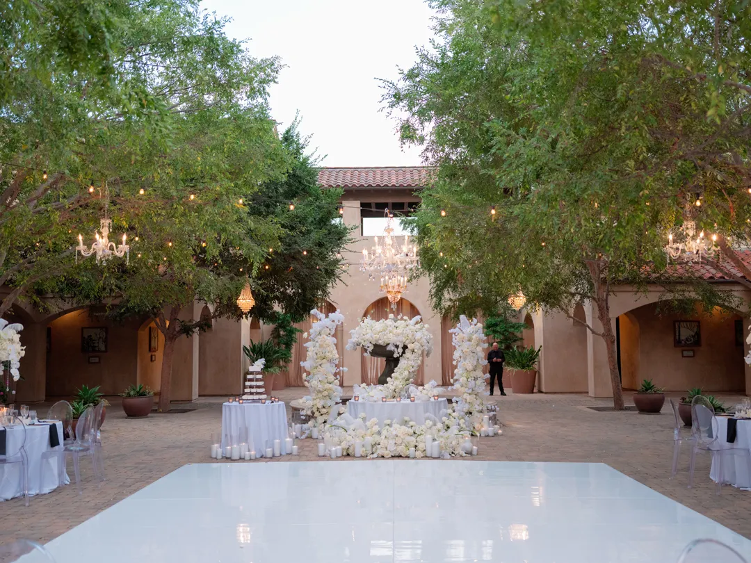 White dance floor facing the flower-covered courtyard fountain.