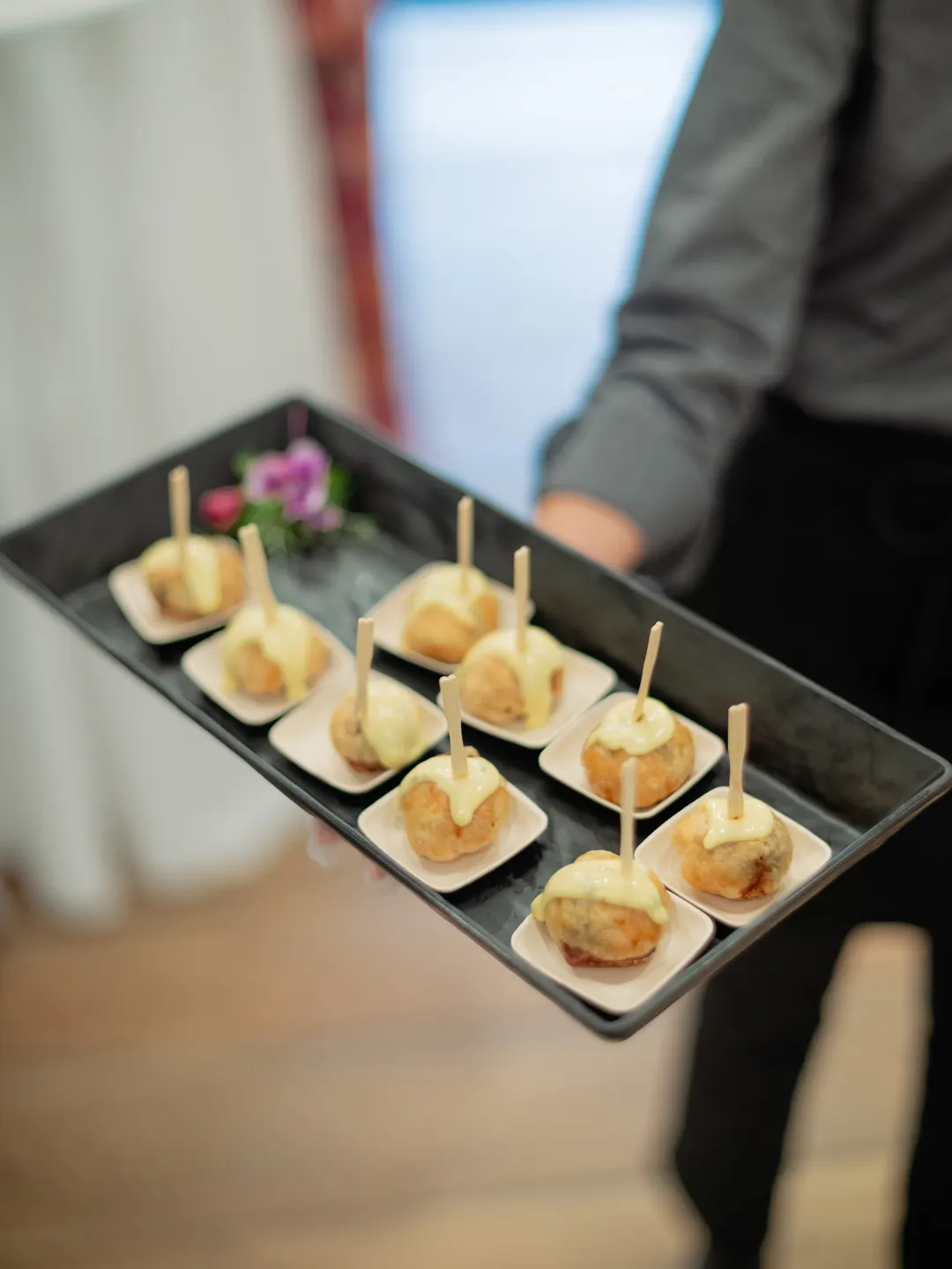 Tray of small golden appetizers served on individual tasting dishes.