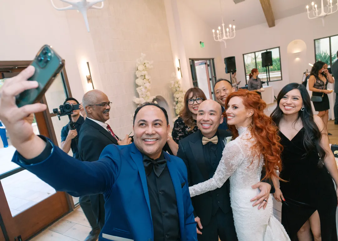 Wedding couple and guests posing together for a phone selfie.