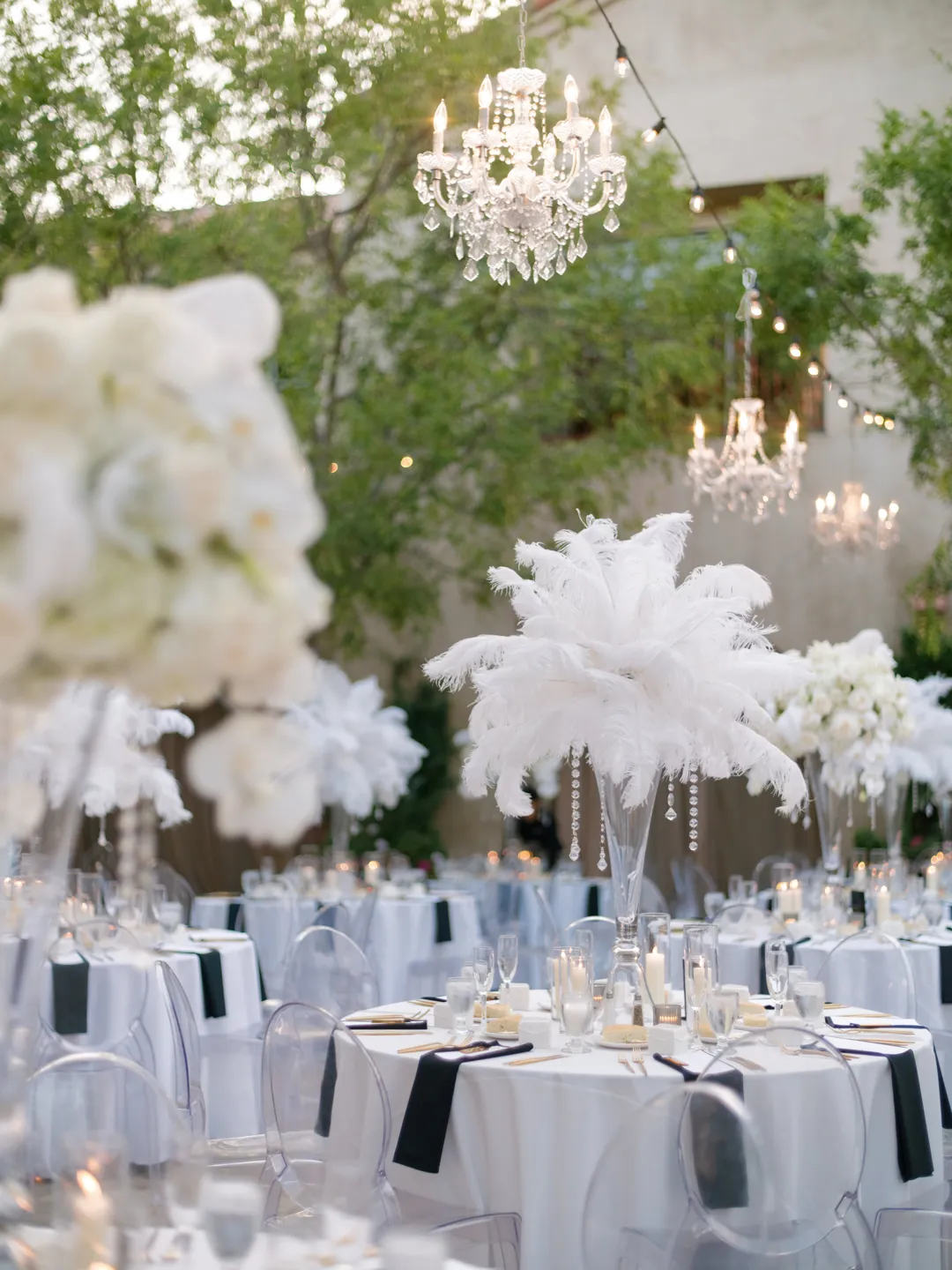 Close-up of a white feather centerpiece above a candlelit reception table.