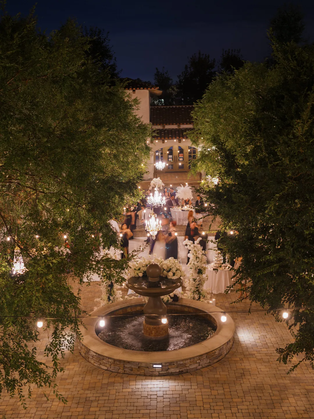 Elevated nighttime view of the illuminated courtyard fountain and reception.