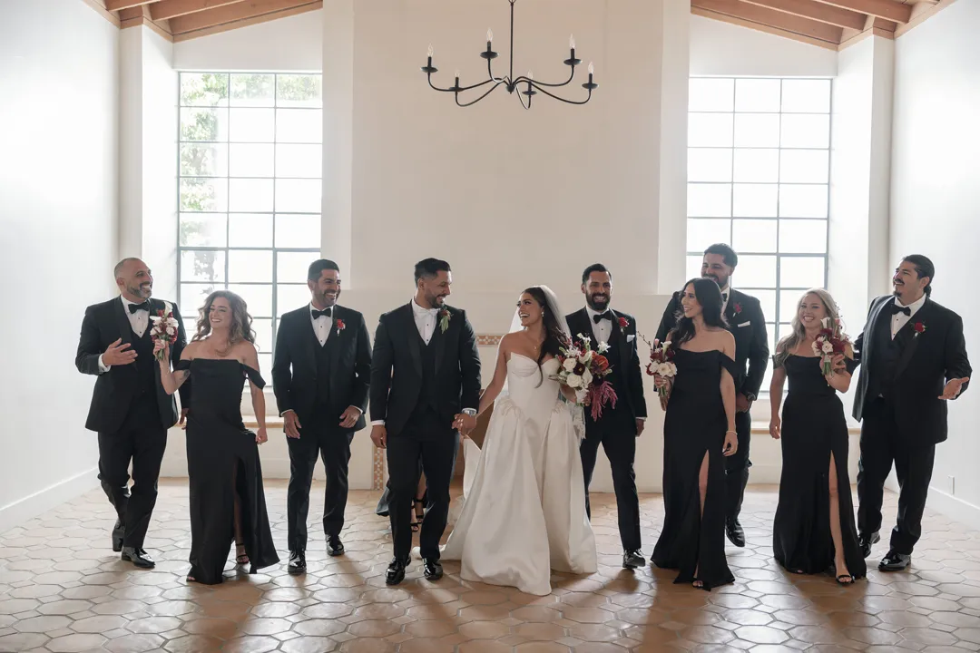 Wedding party posing together in black formalwear with the bride.