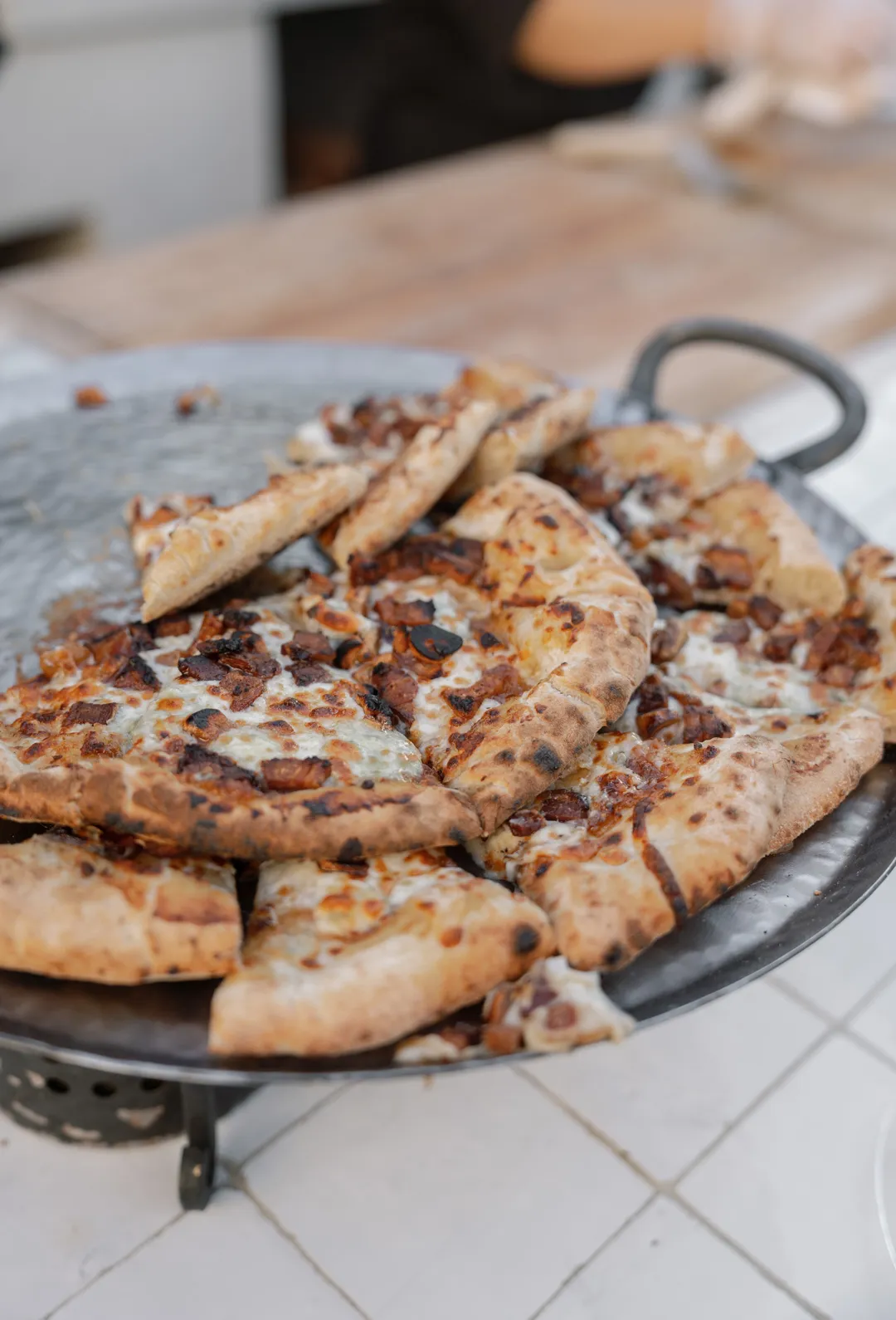 Fresh pizza slices piled on a metal serving platter.