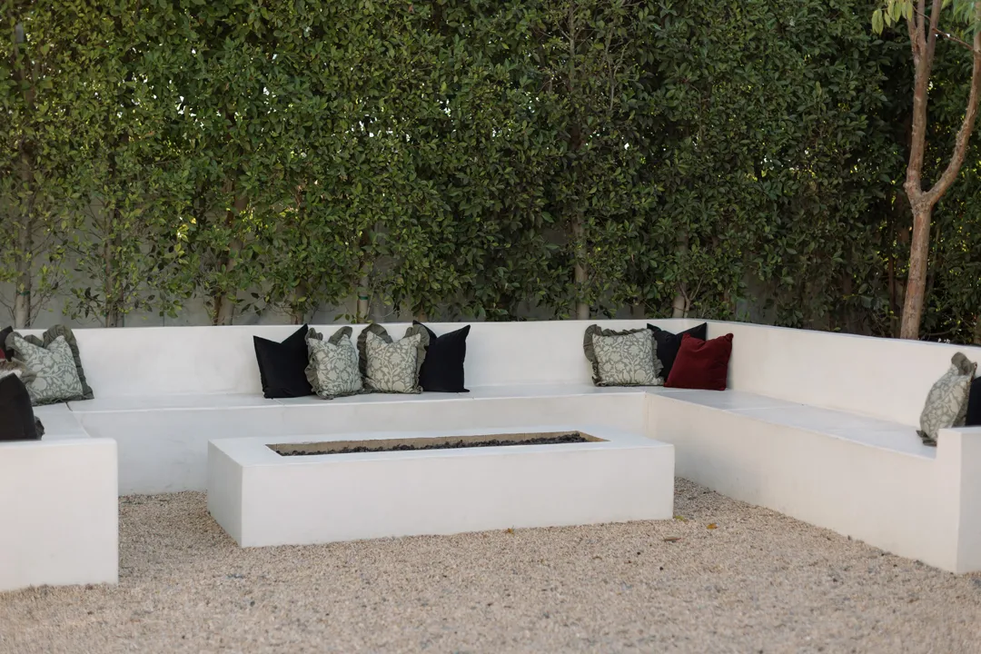 White built-in courtyard seating around a rectangular fire feature.