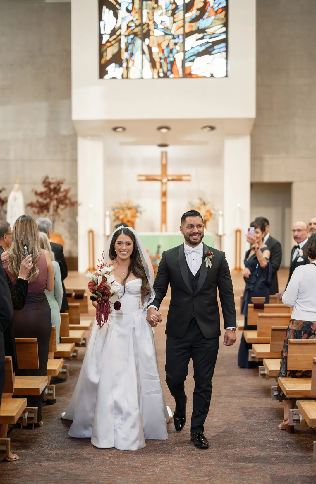 Newlyweds walking down a church aisle after their ceremony.