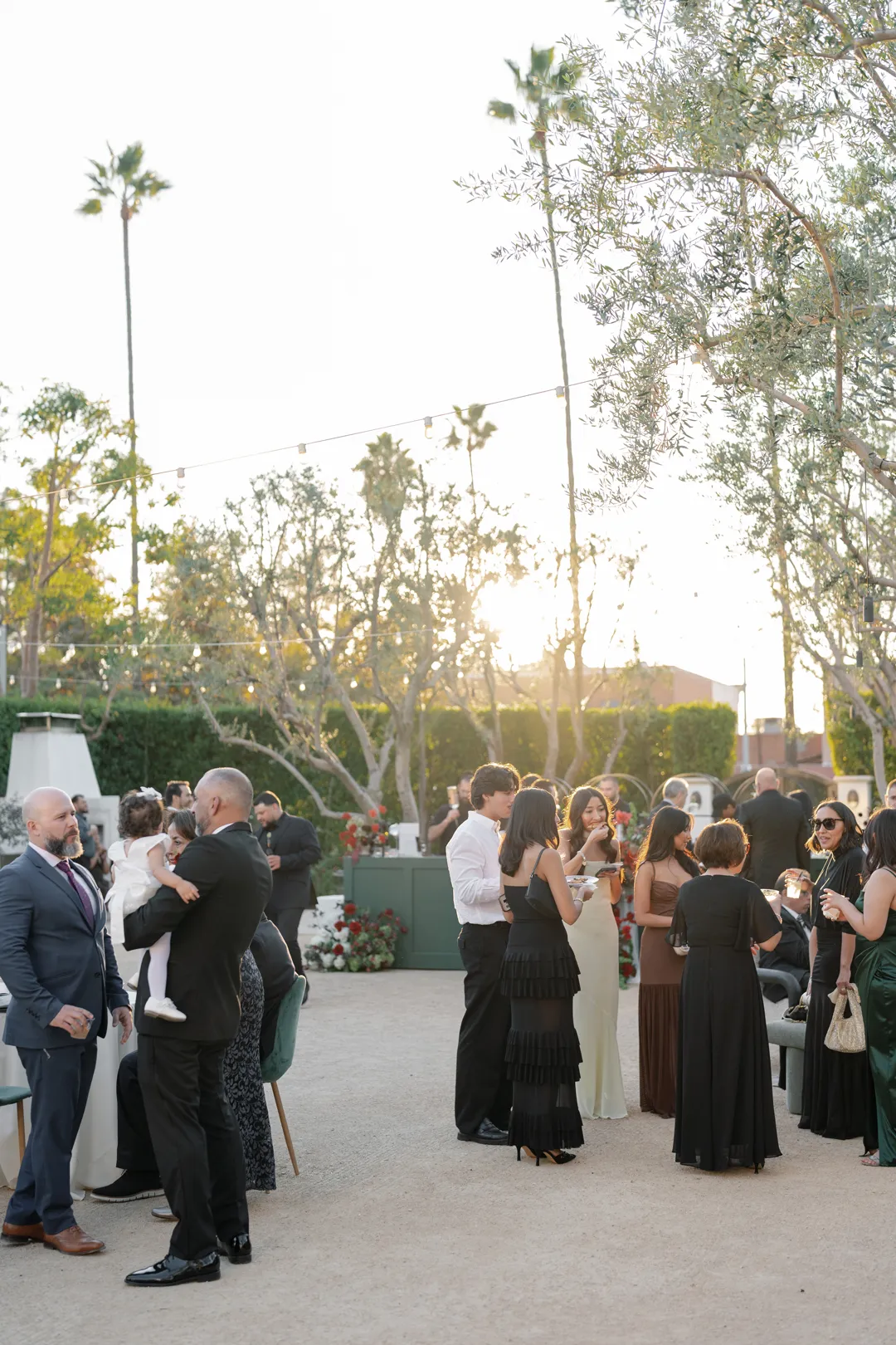 Wedding guests mingling beneath courtyard string lights.