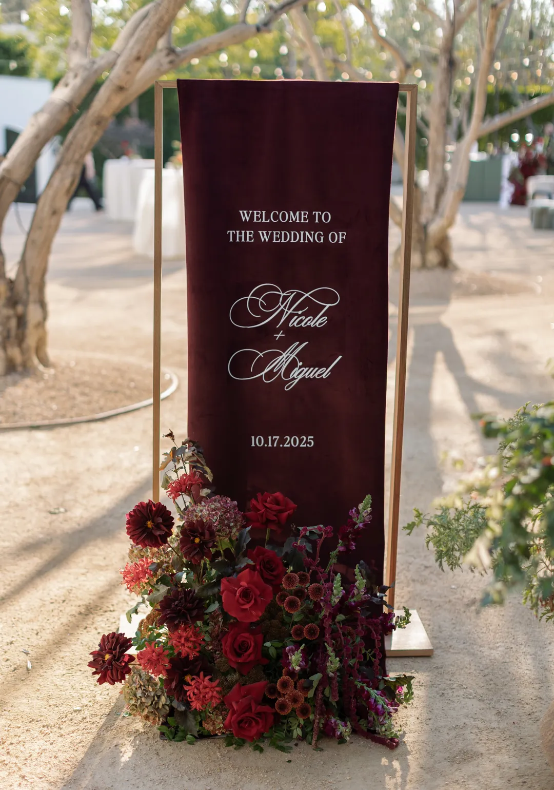Burgundy wedding welcome sign decorated with deep red flowers.
