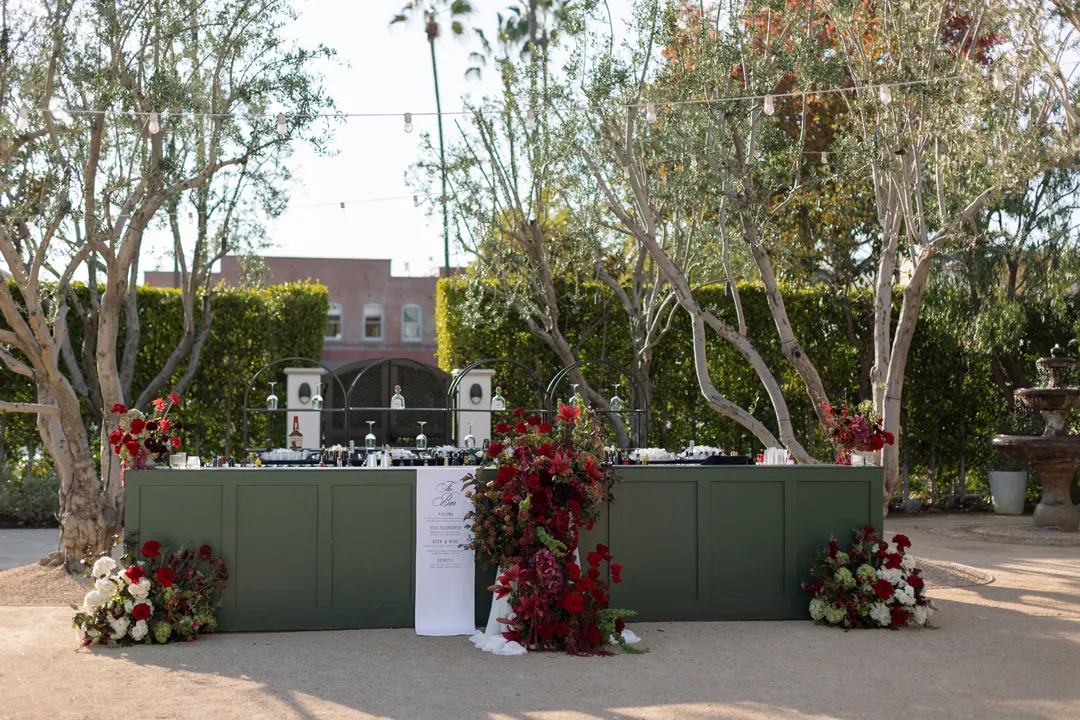 Green outdoor bar decorated with red and burgundy flowers.