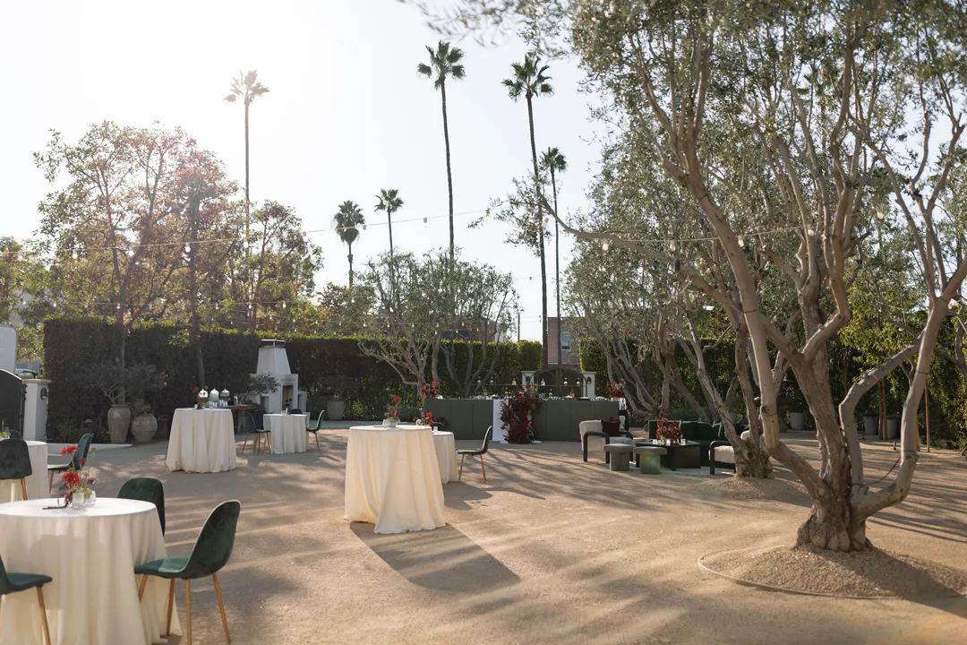 Linen-covered cocktail tables arranged among olive trees.