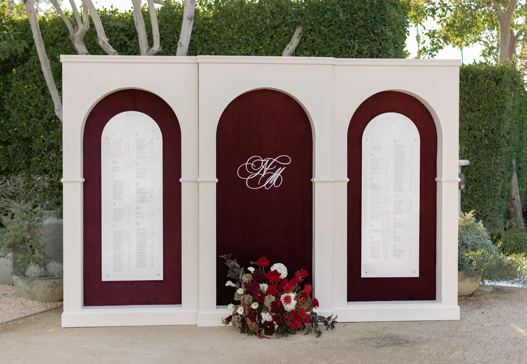 Three-panel burgundy and white wedding seating chart.