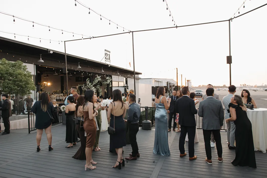 Wedding guests gathering for cocktails on an outdoor deck.