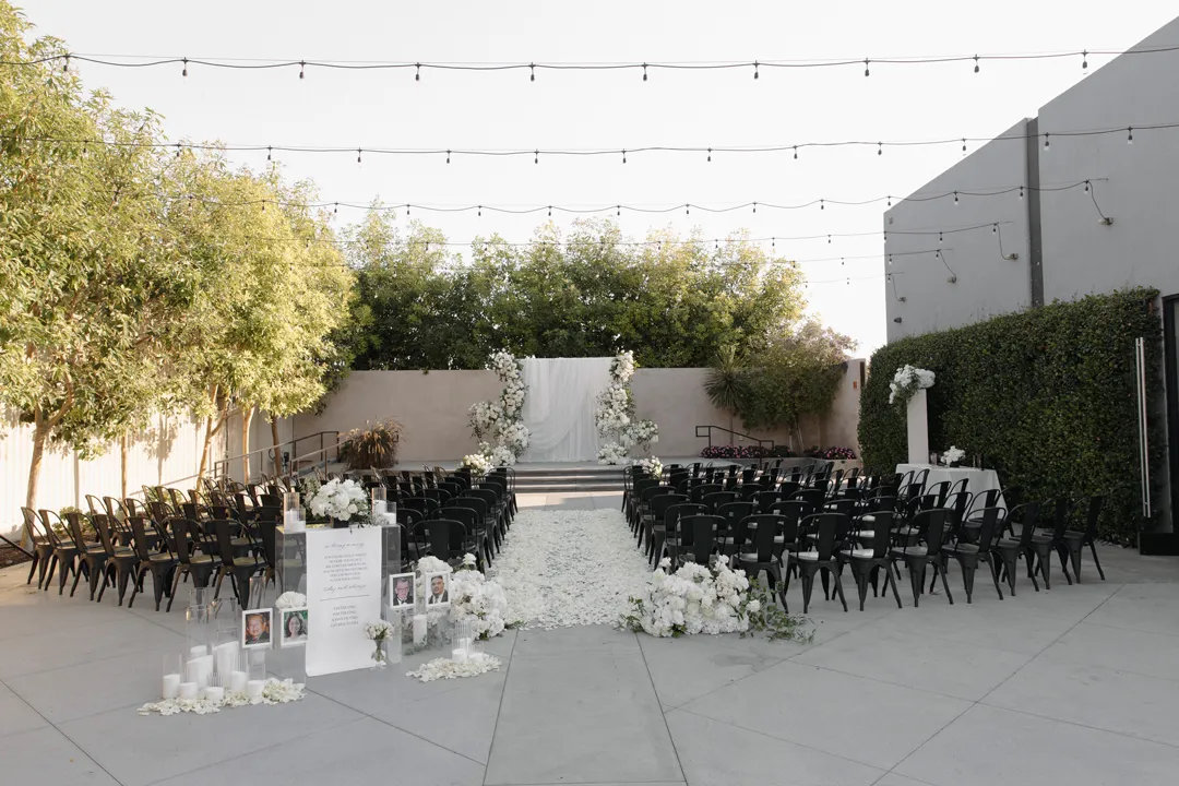Outdoor wedding ceremony space with black chairs and white floral decorations.