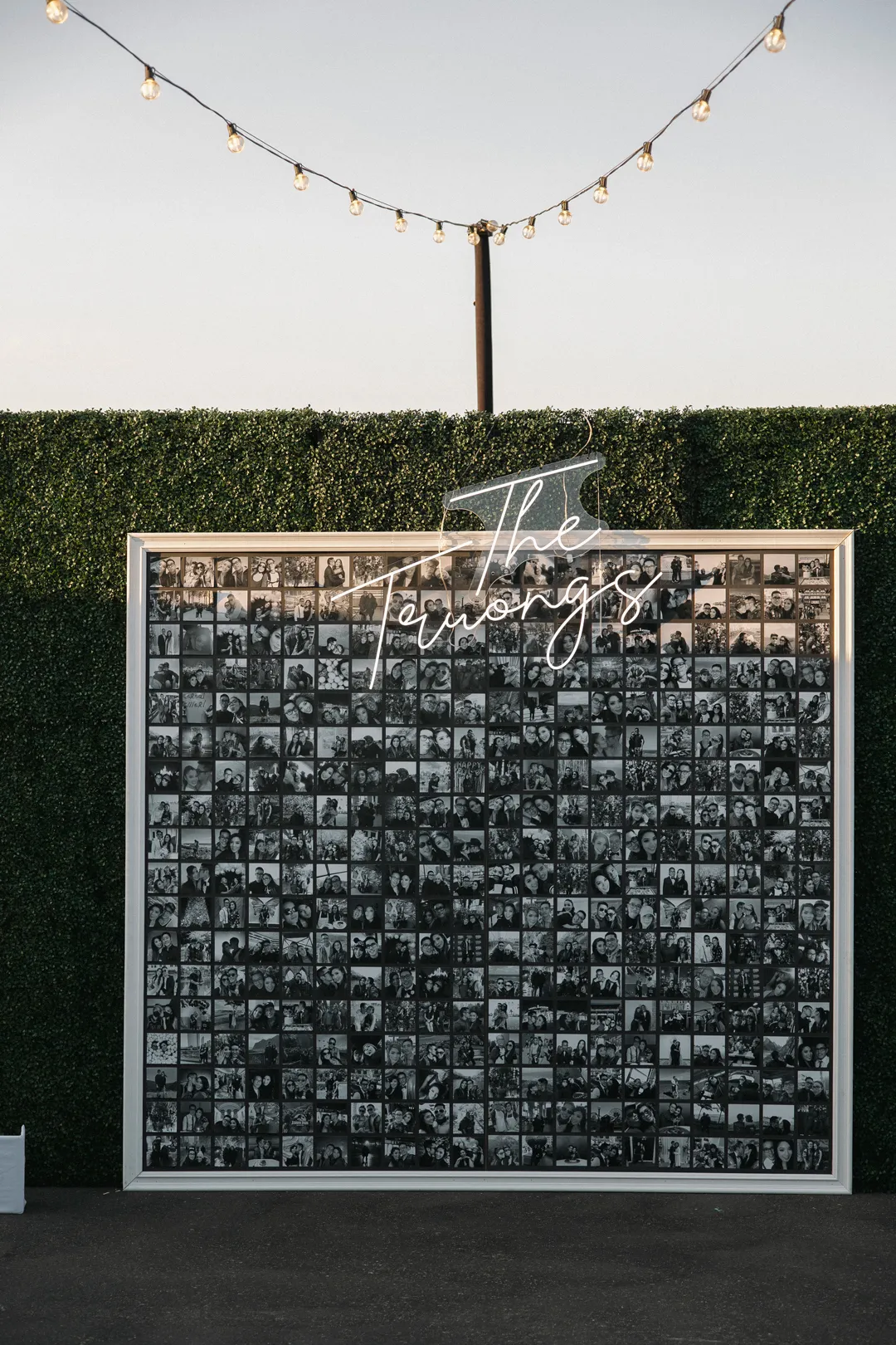 Large display of black-and-white photographs beneath an illuminated script sign.