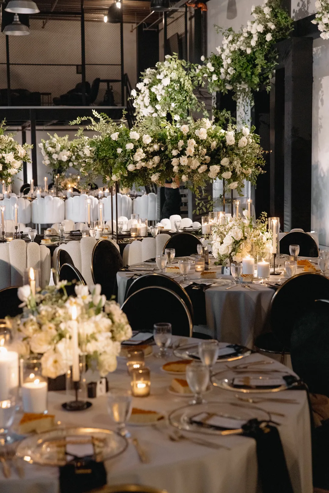 Reception place settings with gold chargers and black napkins.