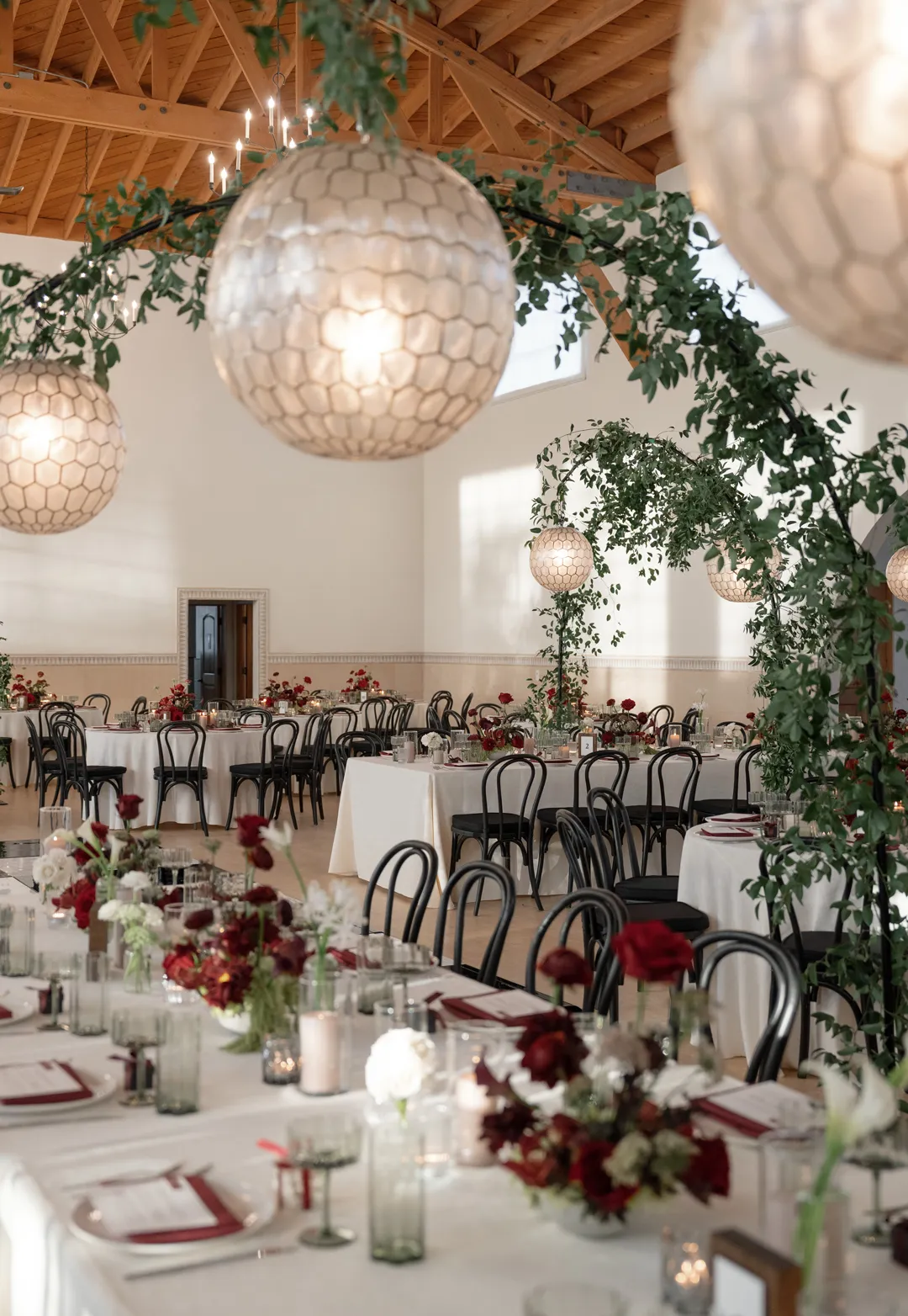 Hanging globe lights and greenery above a long reception table.
