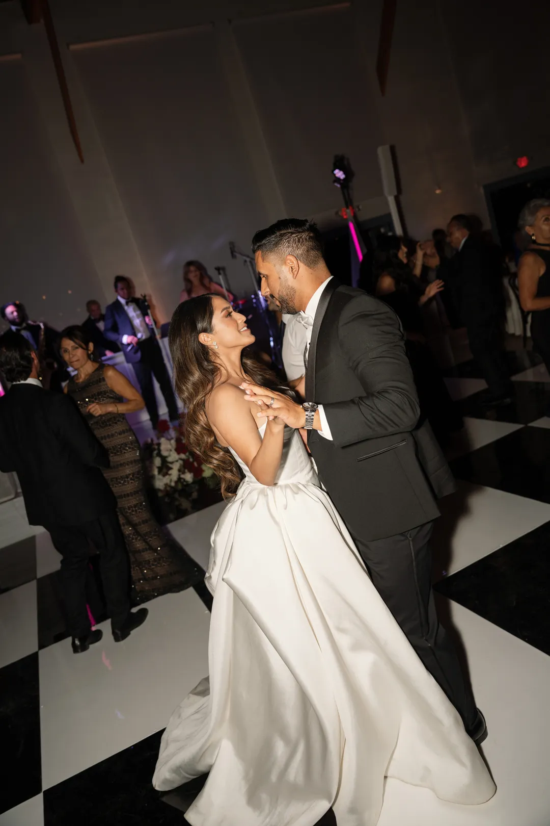 Wedding couple dancing together on a black-and-white floor.