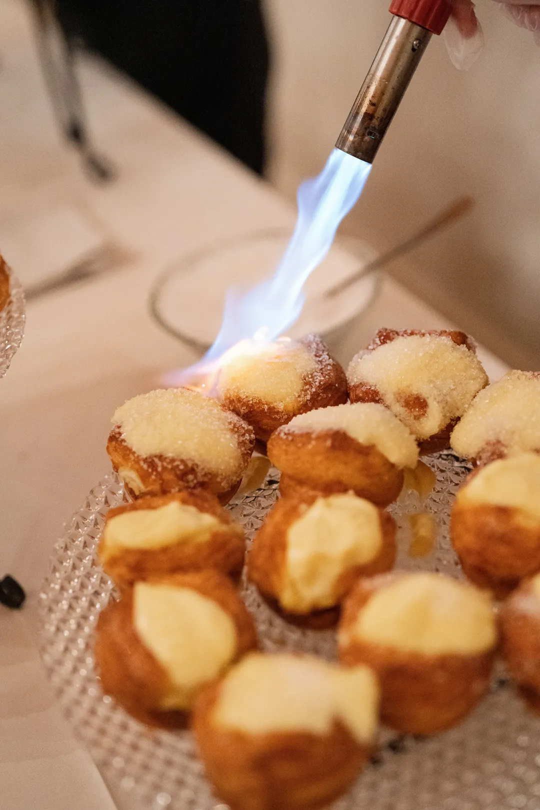 Small filled pastries being finished with a culinary torch.