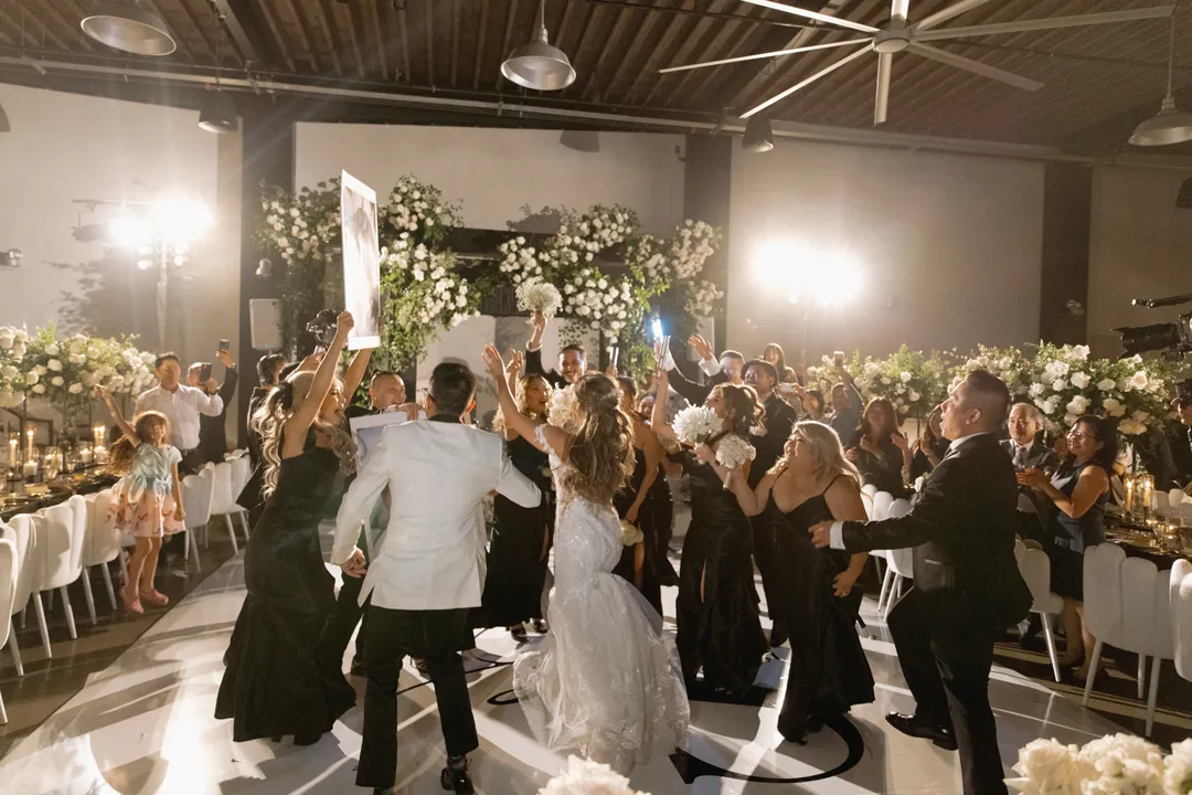 Wedding guests celebrating around the couple on the dance floor.
