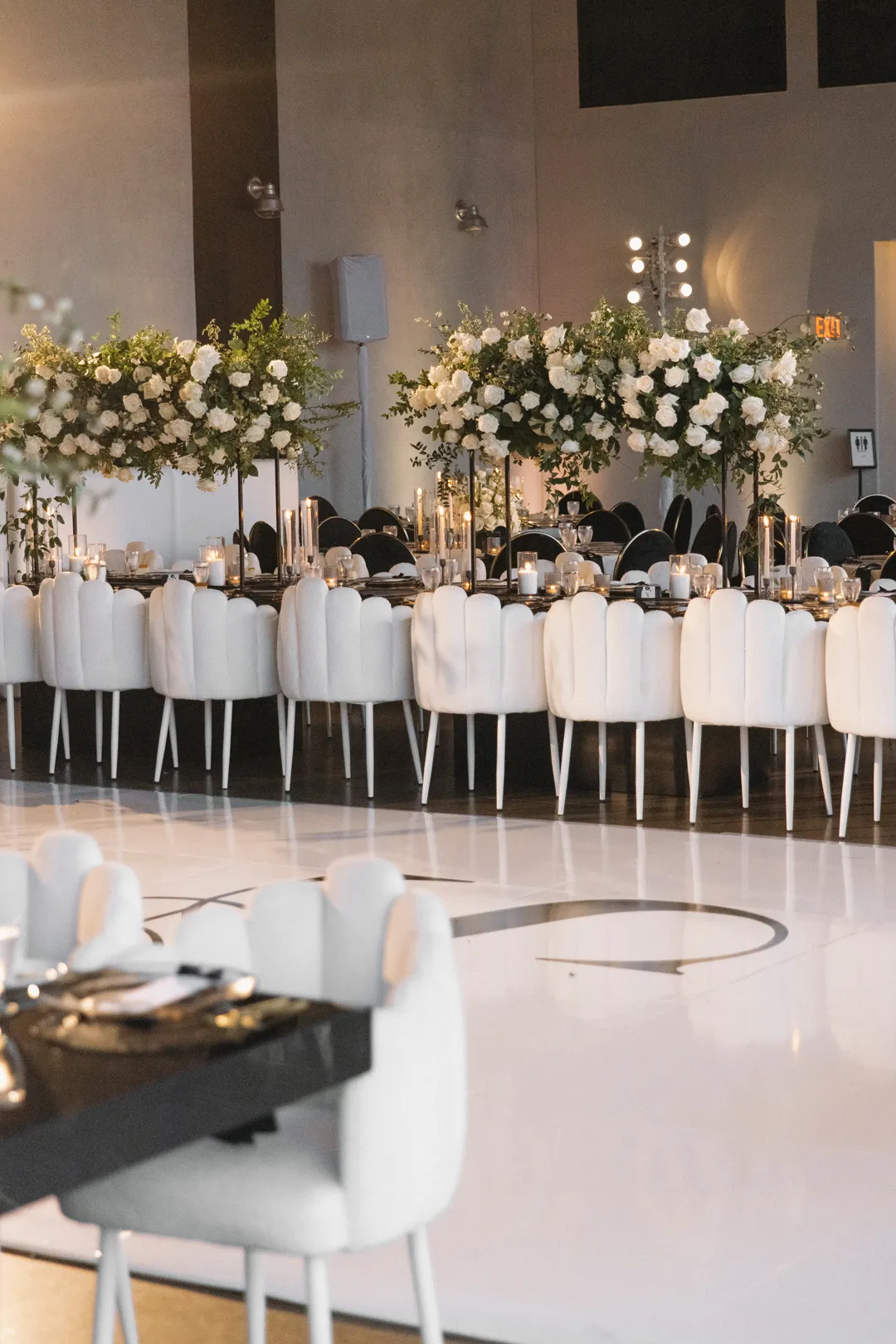 White dance floor beside a long flower-decorated reception table.