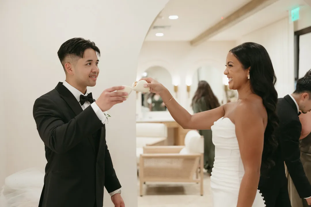 Wedding couple raising small glasses together during cocktail hour.