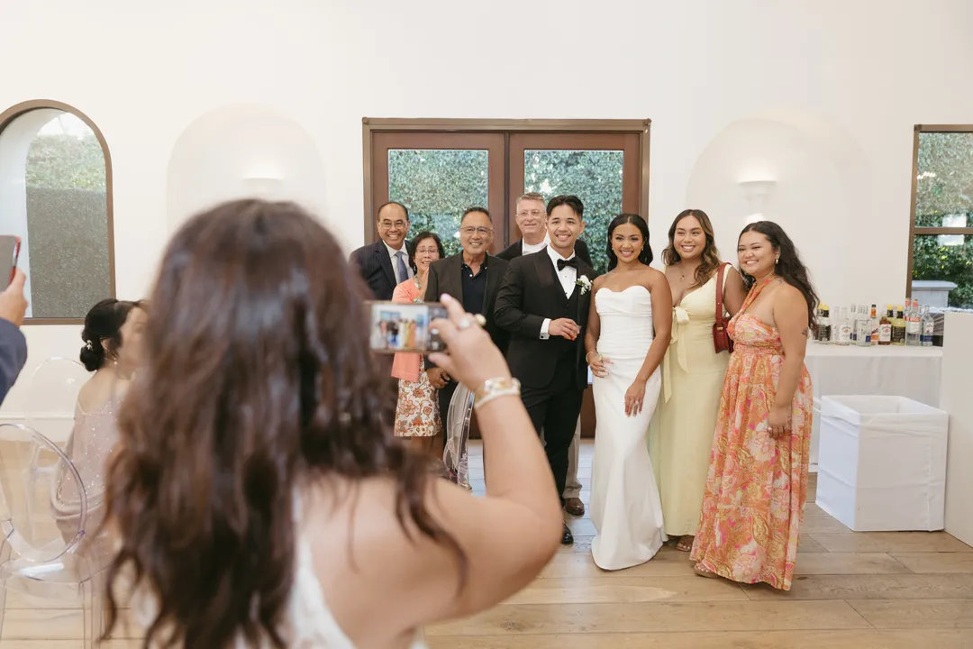 Wedding couple posing with guests for a photograph in the lounge.