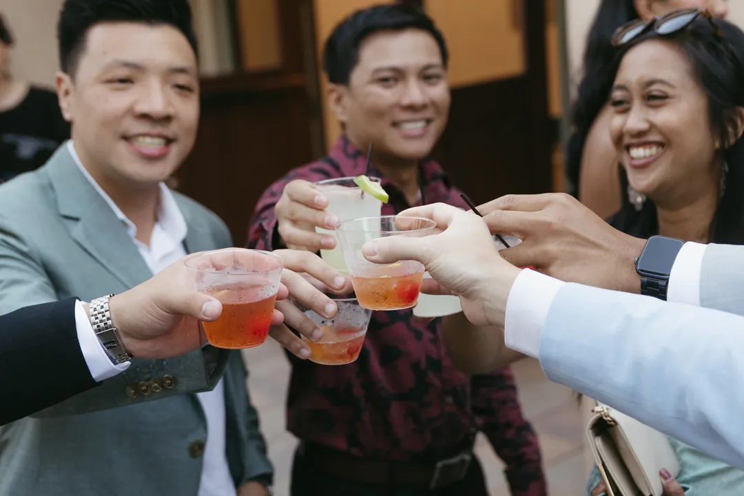 Wedding guests raising colorful cocktails for a toast.