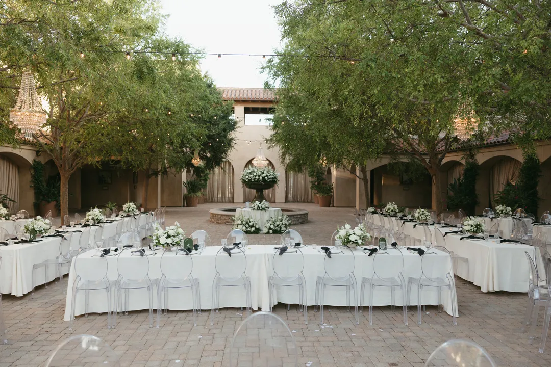 White-linen reception tables arranged around the courtyard fountain.