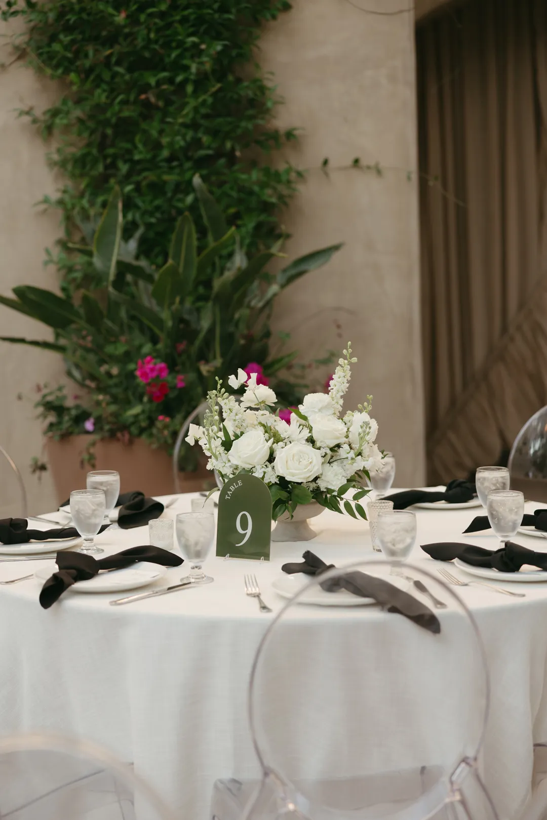 White floral centerpiece and numbered table card on a reception table.