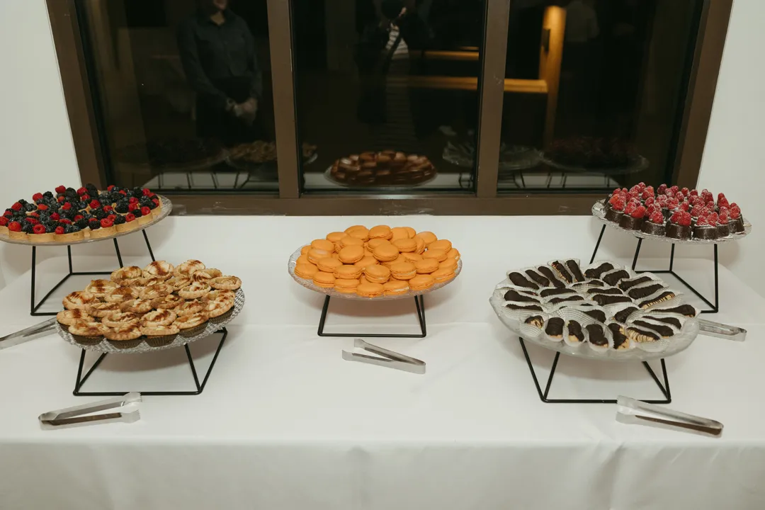 Fruit tarts, macarons and other miniature desserts displayed on platters.