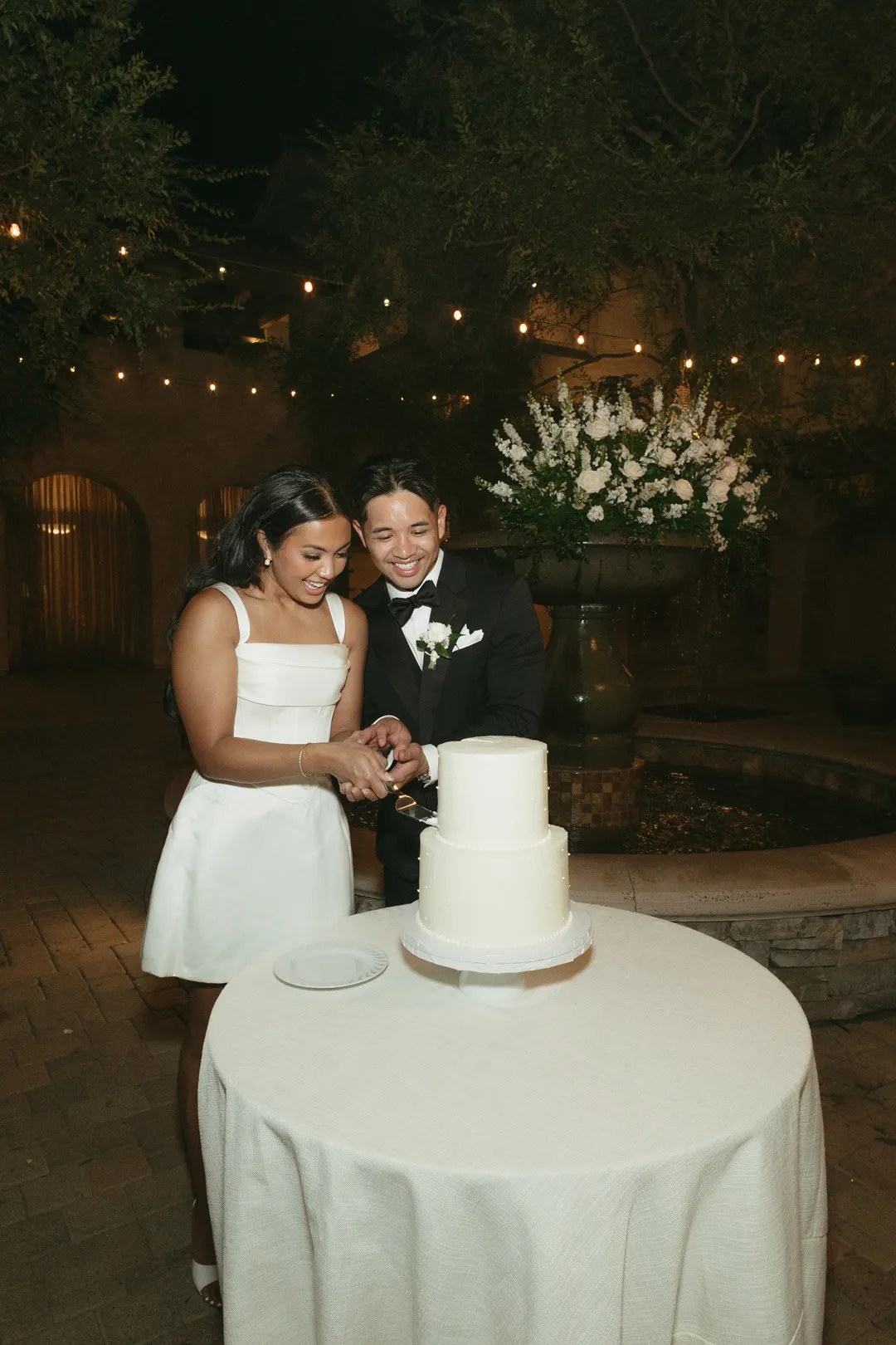 Wedding couple cutting their white wedding cake together.