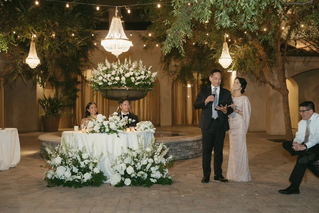 Guests giving a toast beside the couple's flower-decorated table.