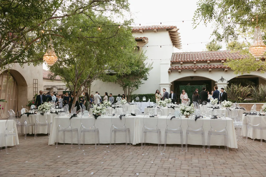 Guests entering the courtyard reception between white-linen tables.